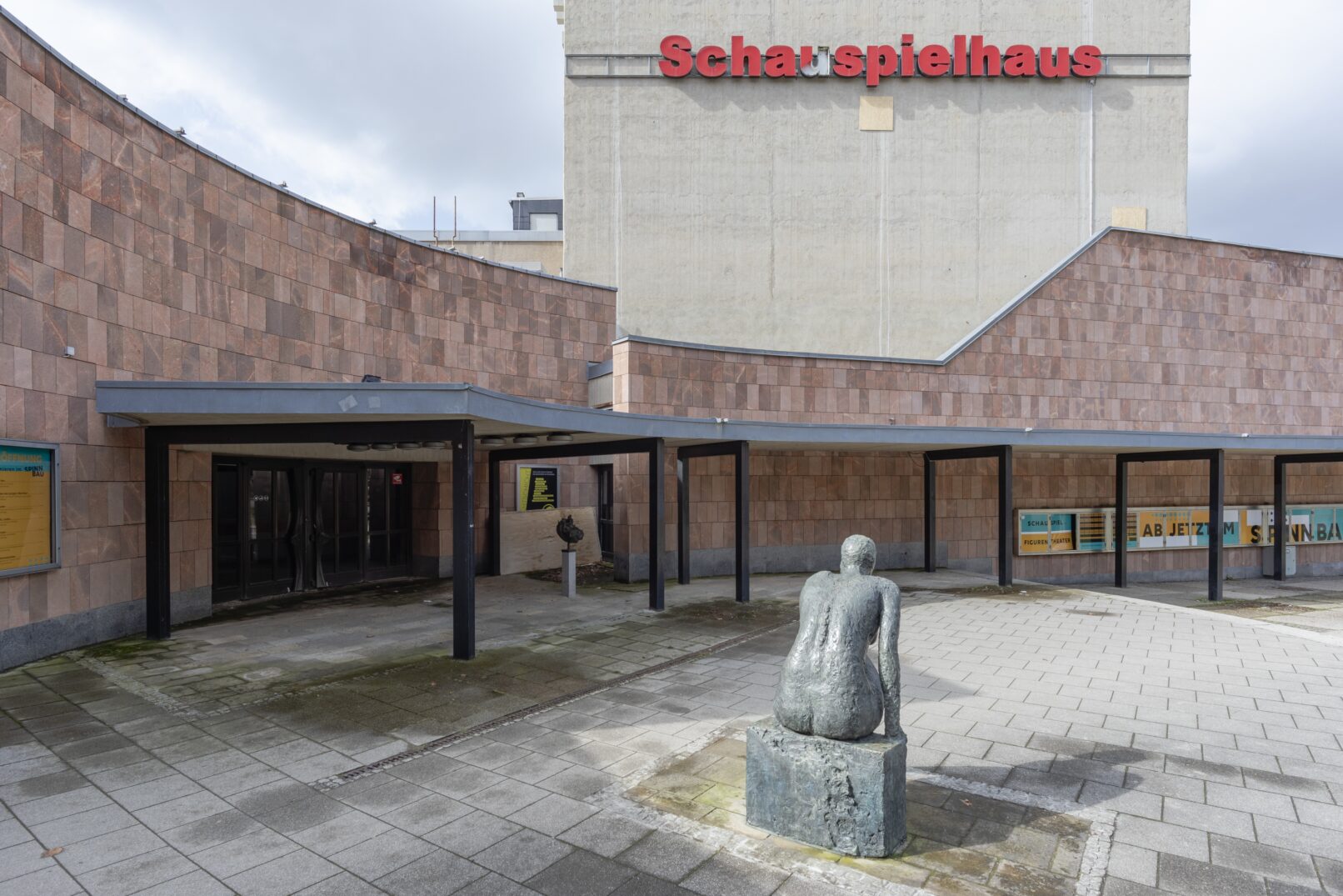 Vorplatz eines Theaters mit einer Skulptur im Vordergrund